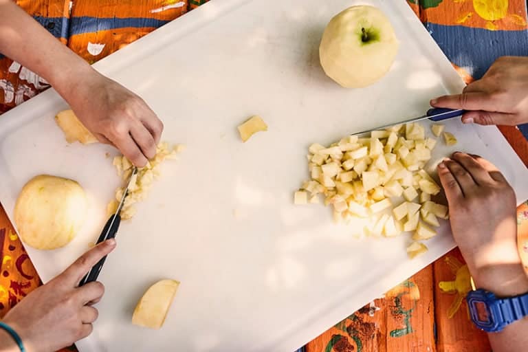 Fresh apple and cheese preparation activity at Eden Village Camp, promoting outdoor fun and edible learning experiences for kids and families.